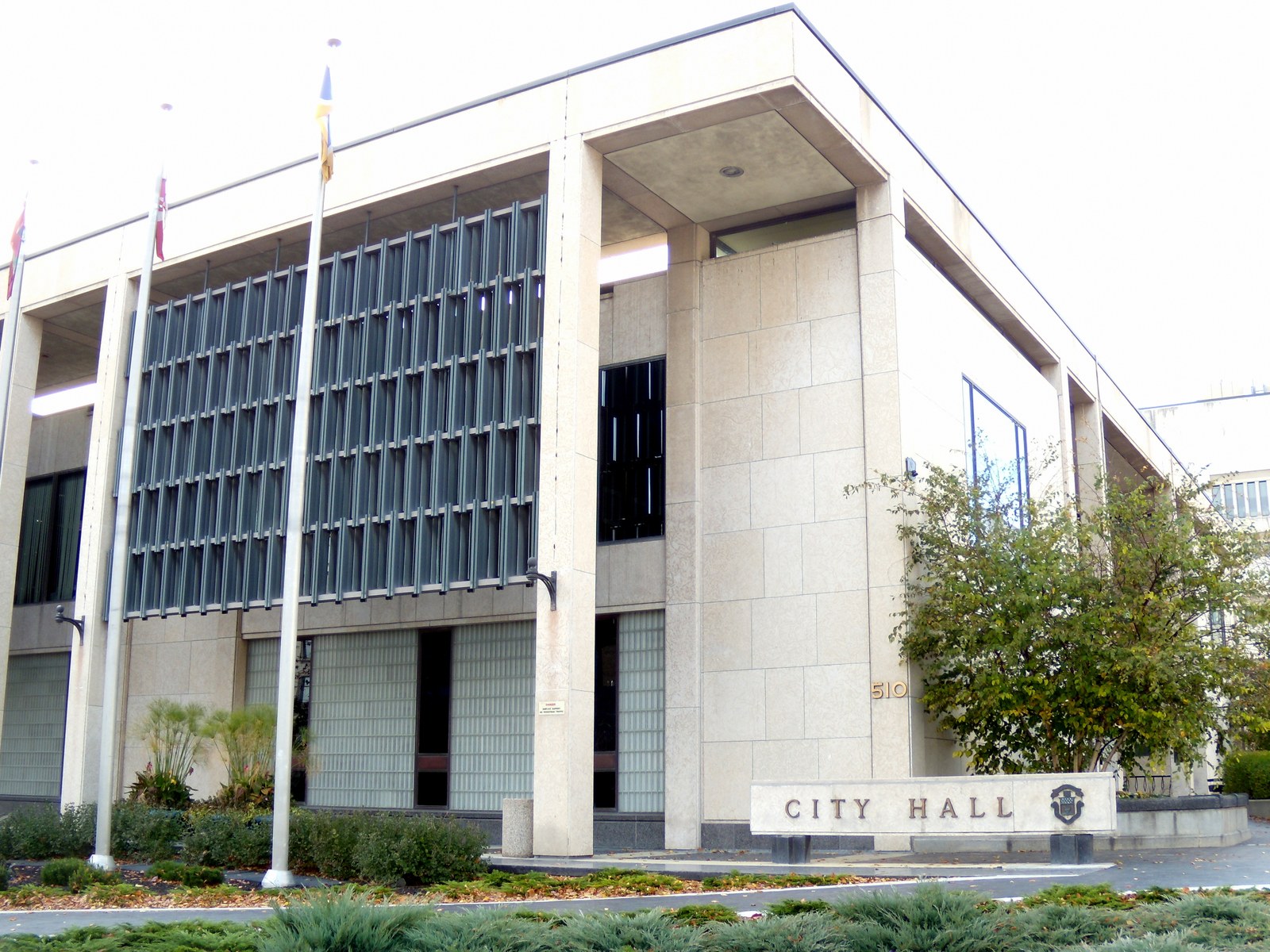 The modernist Winnipeg City Hall council building with flagpoles and a City Hall sign in front